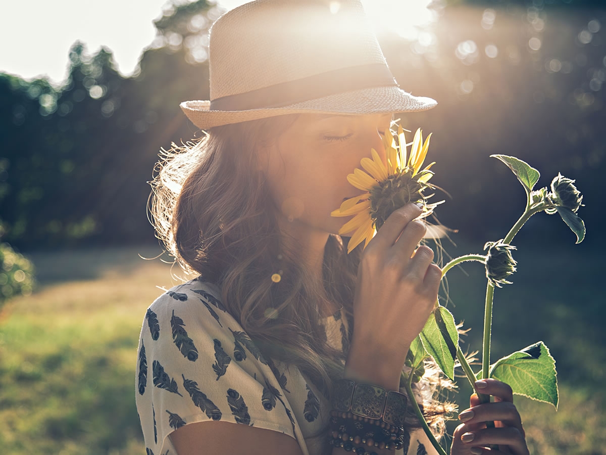 Eine Frau riecht an einer blühenden Sonnenblume